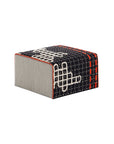 Lille BANDAS puf med sort baggrund, hvidt broderi og orange stikninger.