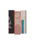 Farverige Bandas tæpper i sort, grå, natur og lyserød, monteret sammen i patchwork-lignende samling.