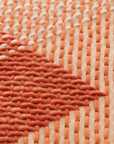 Detalje af CANEVAS GEO i koral – tæt broderi i varierende retninger.