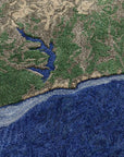 Nærbillede af PLASTIC RIVERS Niger-tæppe, der detaljeret viser flodudløb og kystlinje med dybe blå havtoner, grøn skov og beige landskab - designet som et satellitfoto gengivet i håndtuftet uld.