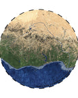 Rundt tæppe fra PLASTIC RIVERS-kollektionen med satellitmotiv af Niger-floden, der viser flodens løb gennem ørken, skov og kyst, gengivet i naturtro farver som beige, grøn og blå.