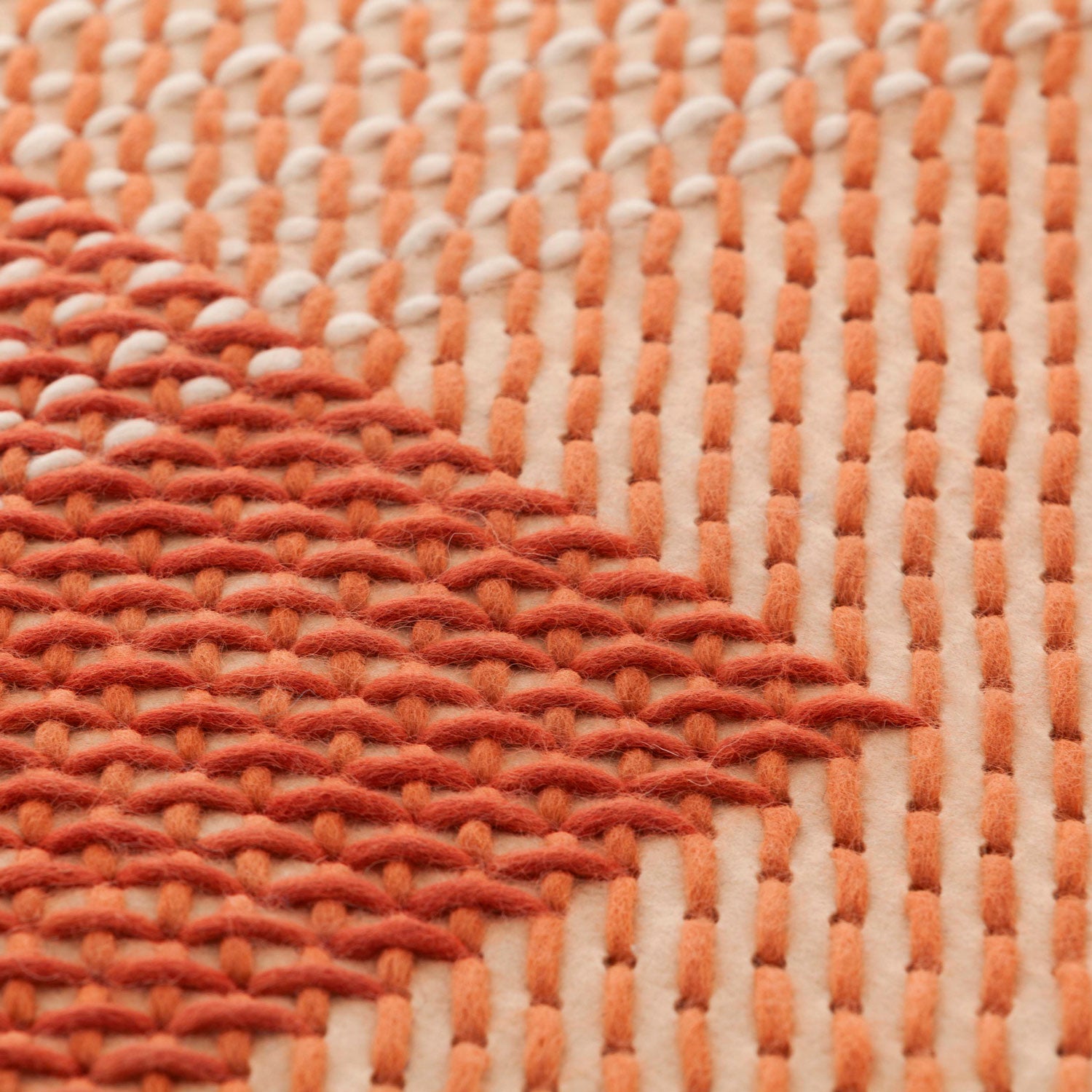 Detalje af CANEVAS GEO i koral – tæt broderi i varierende retninger.